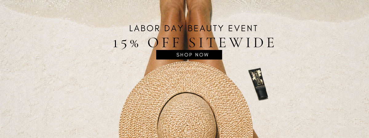 Labor Day beauty event promotional banner with text reading '15% OFF SITEWIDE SHOP NOW' over a top-down view of a person sitting on a beach, wearing a straw hat and holding a black tube product.